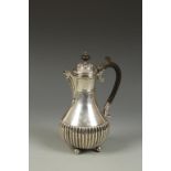 AN EDWARDIAN HOT WATER POT of baluster form with scroll handle and part-fluted decoration,