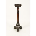 A MAHOGANY TORCHERE with carved and reeded column on platform base with lead feet, early 19th