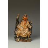 A CHINESE PARCEL-GILTWOOD GUANYIN, seated on a rocky throne, Qing, 18th/19thC, 7.5" high