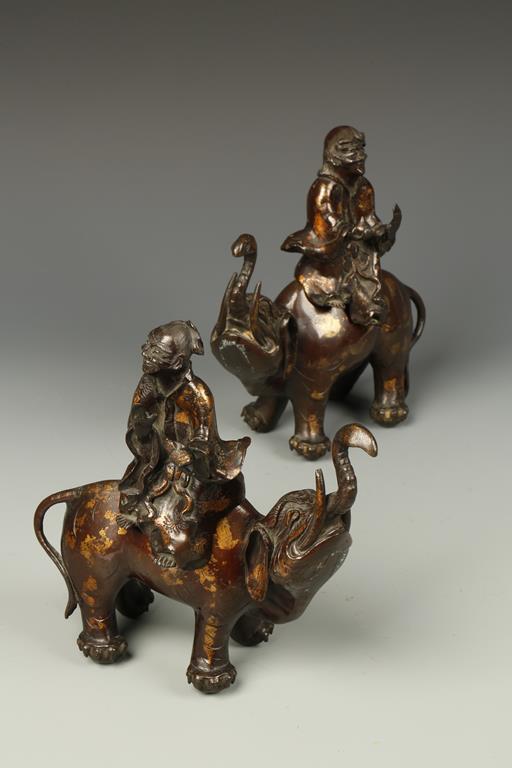A PAIR OF CHINESE PARCEL-GILT BRONZE CENSERS, modelled as Immortals riding elephants, 8" high (2)