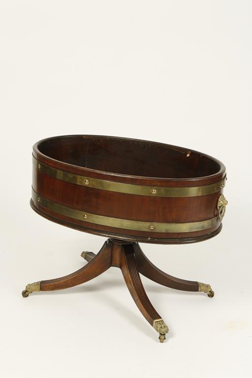 A MAHOGANY AND BRASS BOUND WINE COOLER of open oval form, on four downswept legs with gilt metal