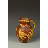 A BARNSTAPLE TYPE SLIPWARE JUG, with yellow glazed bird and flower decoration on brown ground,