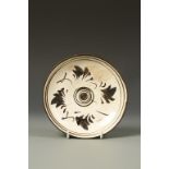 A CHINESE CIZHOU SAUCER DISH decorated with stylised petals, the base with an old collection label