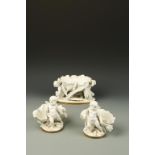 A GARNITURE OF MOORE WHITE GLAZED PORCELAIN TABLE CENTRES, in the form of shells being carried by