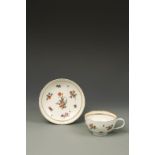A BRISTOL PORCELAIN TEA CUP AND SAUCER with polychrome painted flower and leaf decoration, within