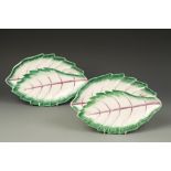 A PAIR OF OVAL LEAF SHAPED DISHES, with puce veining, within a green border, one with the initial '