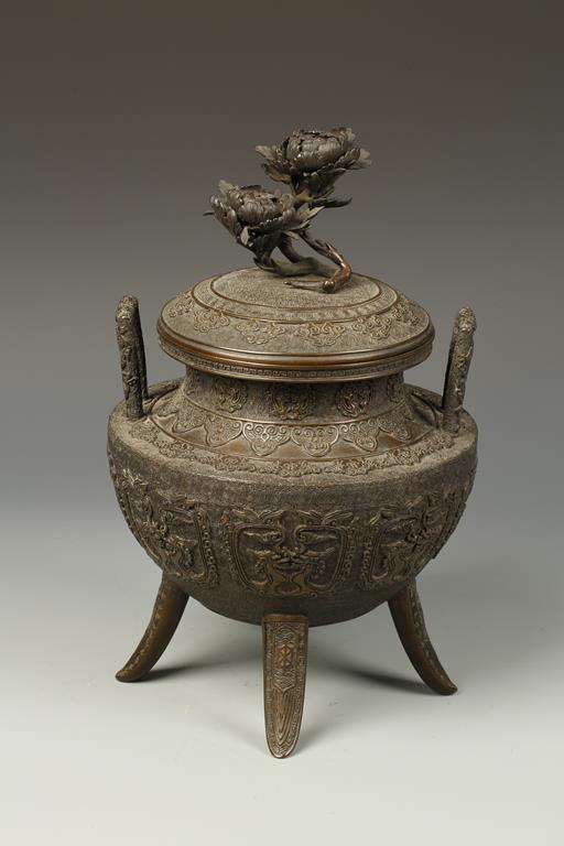 A JAPANESE BRONZE TRIPOD KORO with archaistic relief decoration and a flower finial, signed "