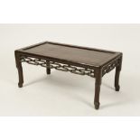 A CHINESE HARDWOOD KANG TABLE with panelled top, pierced frieze and short legs, 30" wide