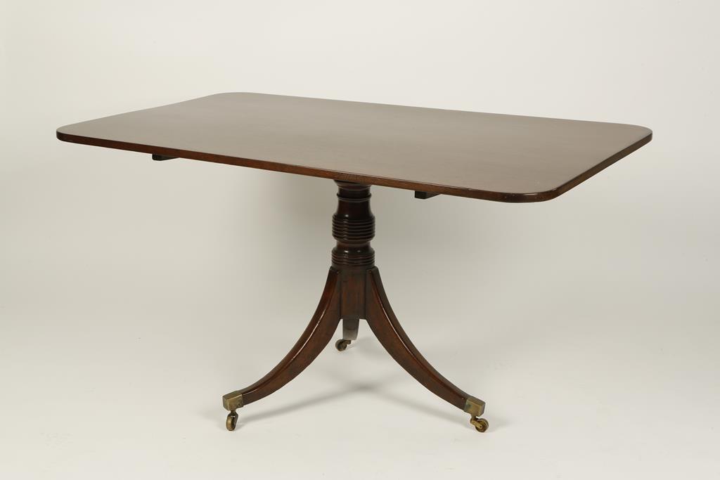 A MAHOGANY TIP-TOP DINING TABLE, the rectangular top on a turned column with three downswept legs,