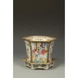 A CHINESE FAMILLE ROSE HEXAGONAL JARDINERE AND STAND, decorated with panels of figures in gardens,
