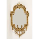 A VICTORIAN GILT FRAMED WALL MIRROR with all over carved decoration and four scrolling candle