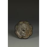 A CHINESE SILVERED BRONZE FOLIATE-FORM MIRROR decorated in relief with Immortals riding cranes and