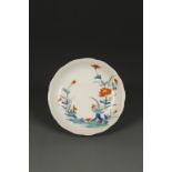 A JAPANESE KAKIEMON SAUCER DISH of foliate form, decorated with flowers in a landscape, Edo