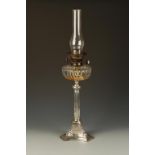 AN EDWARDIAN SILVER MOUNTED OIL LAMP with a cut-glass circular reservoir, cylindrical shade above