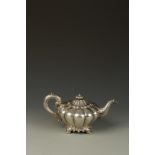 A VICTORIAN TEAPOT of melon form, scroll handle and fluted shell-capped spout, with disc finial,