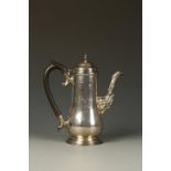 A COFFEE POT of baluster form with scroll handle, domed lid and cast spout, on a spreading