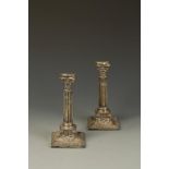 A PAIR OF VICTORIAN CANDLESTICKS of corinthian form with shaped square capitals, the bases applied