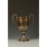 A VICTORIAN PRESENTATION TROPHY CUP of circular tapering form with reeded handles and stiff leaf