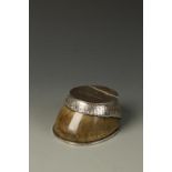 AN EDWARDIAN SILVER MOUNTED "HORSES HOOF" INKWELL with hinged cover engraved "Manxman", by L.B &