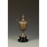 A TROPHY CUP AND COVER of campana form, with pull-off cover and flowerhead frieze, on an