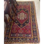 An old Eastern rug, with flowerhead and mask decoration, on red and blue grounds, within yellow