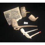 A large clay pipe decorated with a bearded figure, another with a large exhibition building and