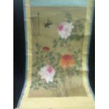 A Chinese rolled scroll painting with birds flying amongst flowering foliage