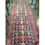 An Afghan design runner, with multi-coloured motifs, on black and red ground, 190" long x 40" wide