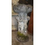 A reconstituted stone bird-bath, supported by cherubs, 21.5" high