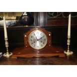 A mahogany and mother-of-pearl inlaid mantel clock and a pair of similar candlesticks