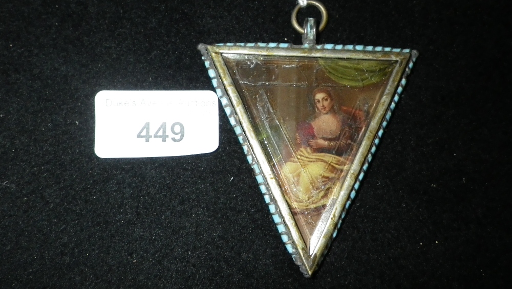 A triangular pendant set with a portrait of a woman in a landscape