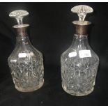 A pair of cut-glass decanters with silver rims