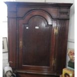 An 18th century oak hanging corner cupboard of architectural form, the arched door flanked by reeded