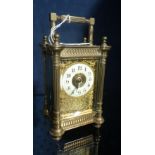 A brass-cased carriage clock with filigree mount and decorated case