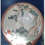 A Chinese plate decorated with an exotic bird within a landscape, with decorated rim, on a