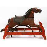ANTIQUE CARVED WOOD & UPHOLSTERED CHILD'S ROCKING HORSE, L 39": Fitted on a painted red stand,
