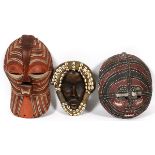 AFRICAN CARVED MASKS, THREE, H 11"-16 1/2":  One  mask having painted ochre accents and holes for