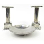 Hugh Wallis stainless steel Arts and Crafts style candlesticks and a pin tray, impressed initials,