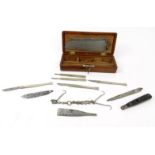 Selection of surgeon's tools including a saw, scalpel, knives and hooks, housed in a mahogany box,