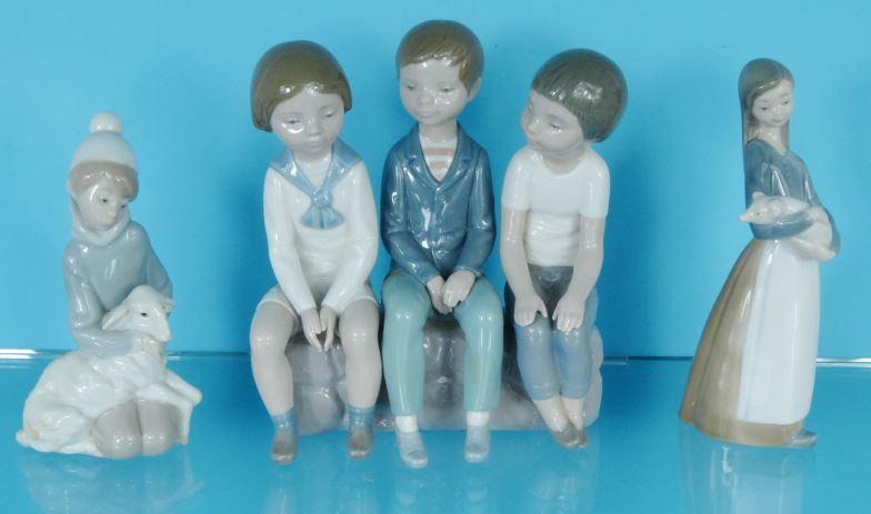 Three boxed Lladro China figures - one of three young figures seated, a girl with a pig and a boy