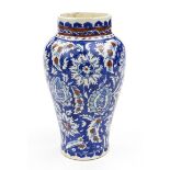 Middle Eastern Iznik style pottery baluster vase painted with flowers onto a blue ground, 24cm