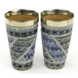 Pair of Doulton Lambeth stoneware beakers with relief moulded decoration and silver plated mounts,