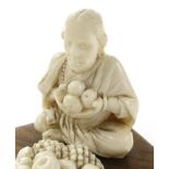 Indian carved ivory figure of a female fruit seller raised on a wood stand, bearing a paper label to