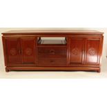 Oriental hardwood sideboard fitted with four cupboard doors, two central drawers and a pull out