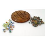 Wooden solitaire board with a selection of assorted marbles including coloured glass examples,