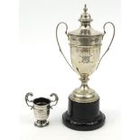 Two silver trophies - one with a cover and hardwood stand, the larger 16.5cm high : For Condition