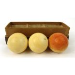 Three ivory snooker balls - one with red staining, housed in a cardboard box, each 4.5cm