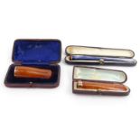 Two boxed amber coloured cheroot holders - one with a 9ct gold top, together with a boxed lady's