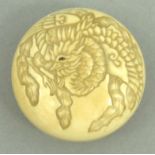 Oriental ivory toggle Netsuke carved with a mythical bird and floral back, 4cm diameter : For