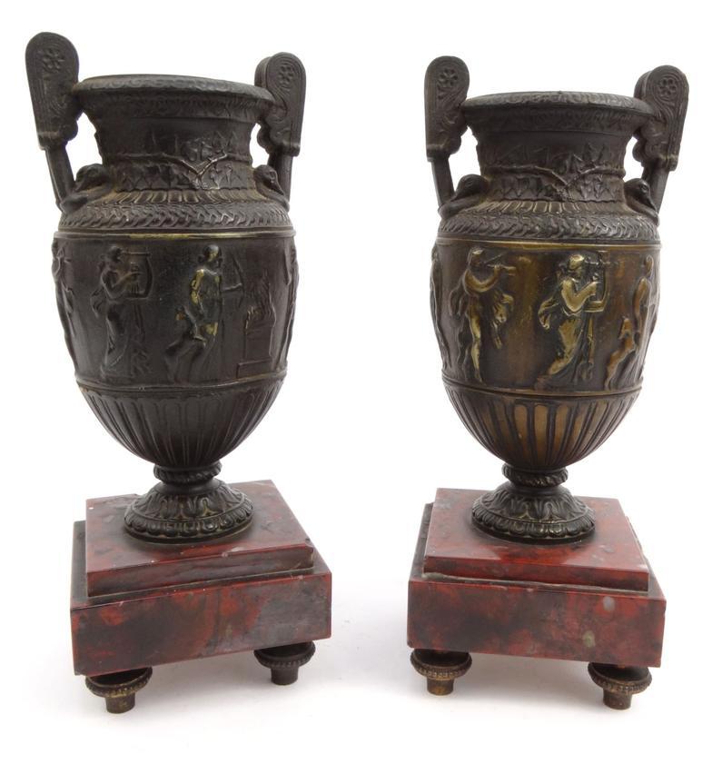 Pair of bronze urns decorated with classical scenes mounted on red marble bases, 23.5cm high : For
